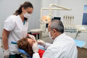 Dentist treating a patient with an assistant